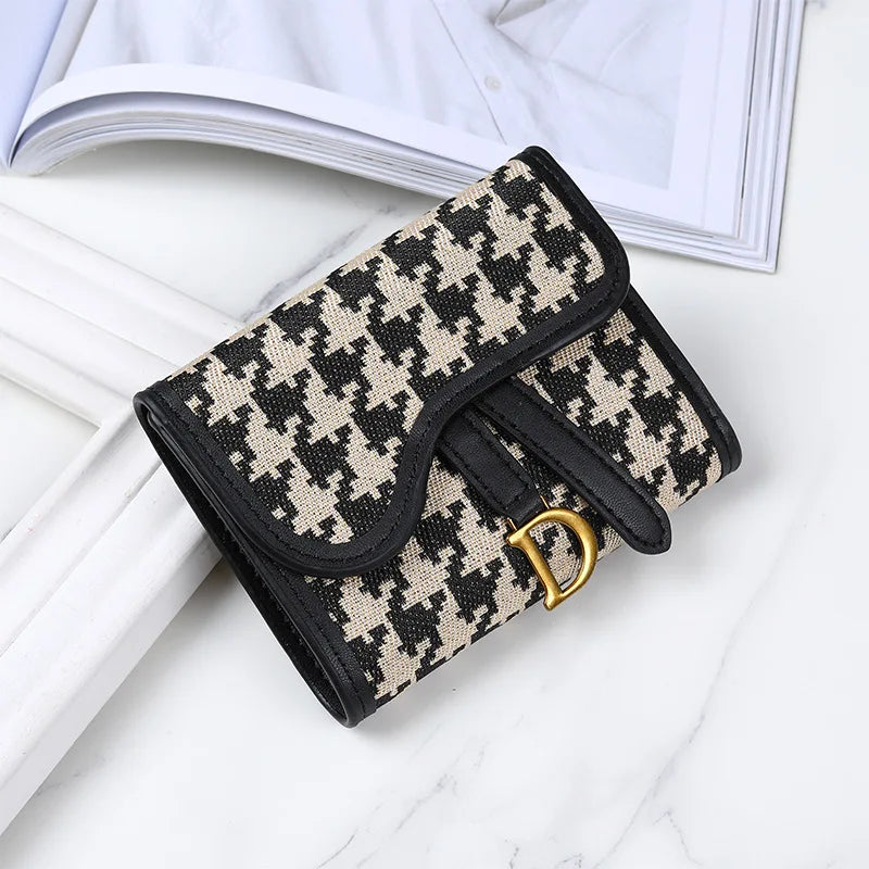 Portefeuille avec porte-cartes noir et beige sur une surface en marbre blanc à côté d'un livre ouvert.