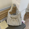 A light gray plaid nylon drawstring tote bag resting on a dark surface next to a book.