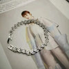 A close-up of a gold stainless steel charm bracelet with portrait pendants worn by a model.