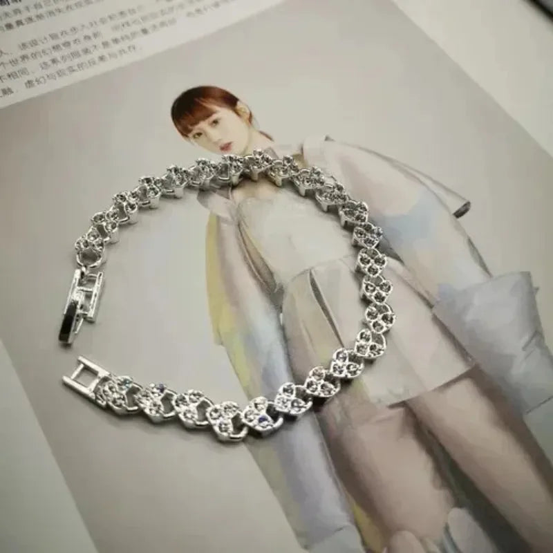 A close-up of a gold stainless steel charm bracelet with portrait pendants worn by a model.
