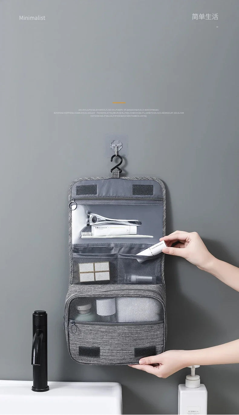 Un sac organisateur en tissu gris portable accroché au mur, affichant divers petits objets à l'intérieur.