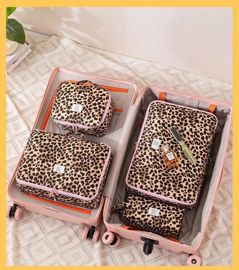 A pink travel makeup organizer bag with a leopard print lining and exterior, shown open on a light surface.