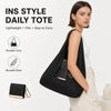 Une femme tient un sac de courses noir en nylon pliable sur son épaule, à côté d'un petit portefeuille noir.