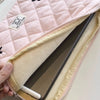 A pink quilted laptop sleeve with a light beige lining and a small tag is shown being held.