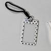 A white card holder with a rectangular frame and black polka dots is attached to a black lanyard.