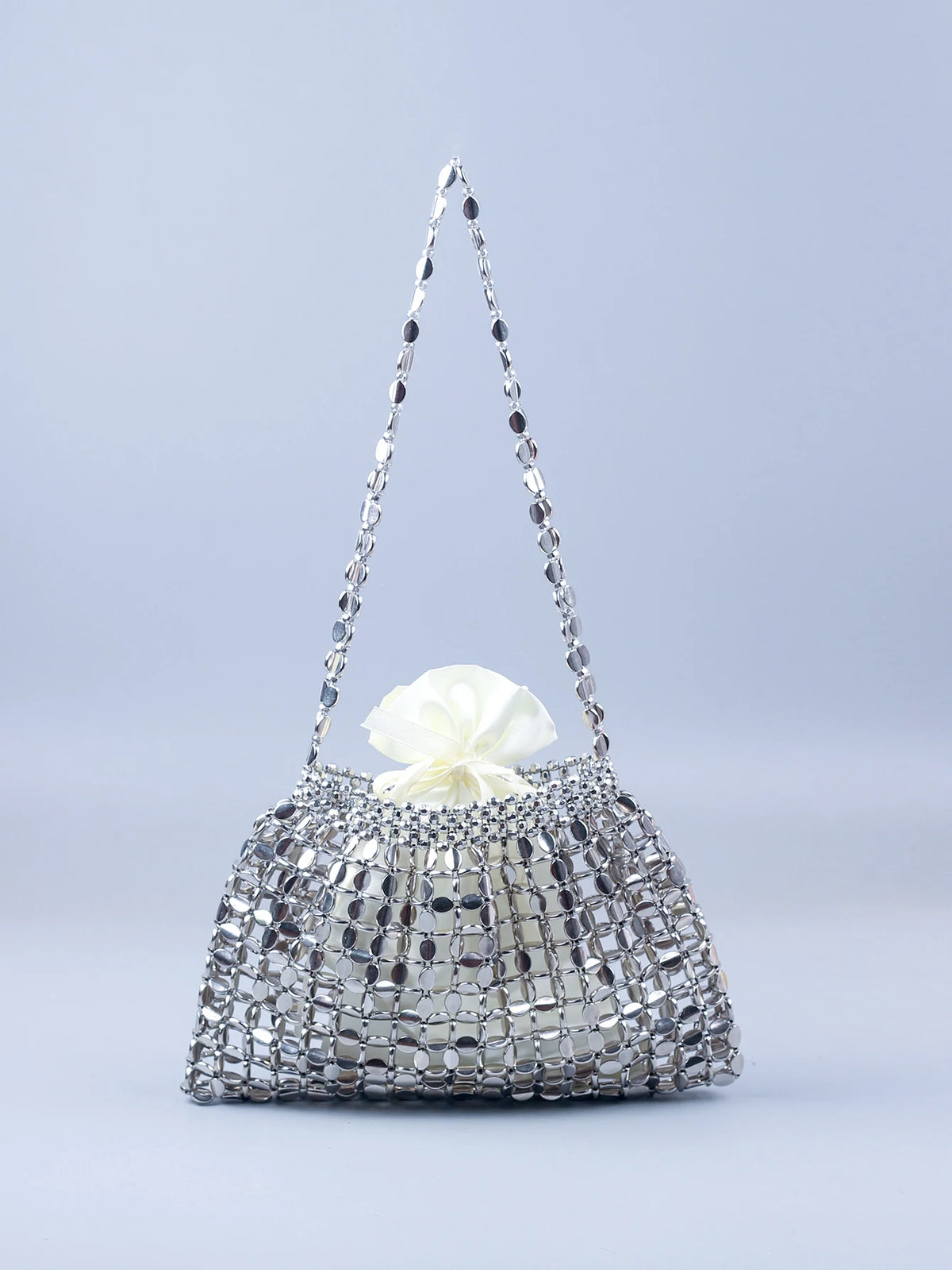 A handmade dumpling bag covered in silver and gold beads with a sheer, beaded handle.