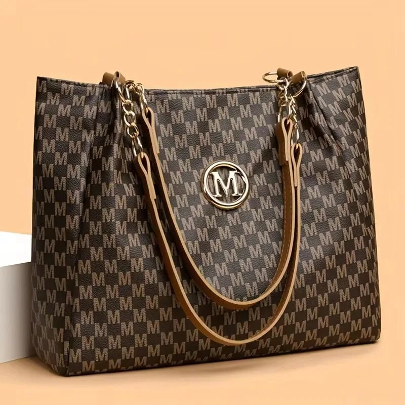 A dark brown geometric monogram print tote bag with gold hardware and leather straps.
