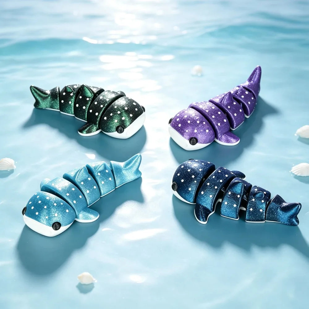 Three colorful 3D printed devil ray figurines in shades of green, purple, and blue floating on light blue water.