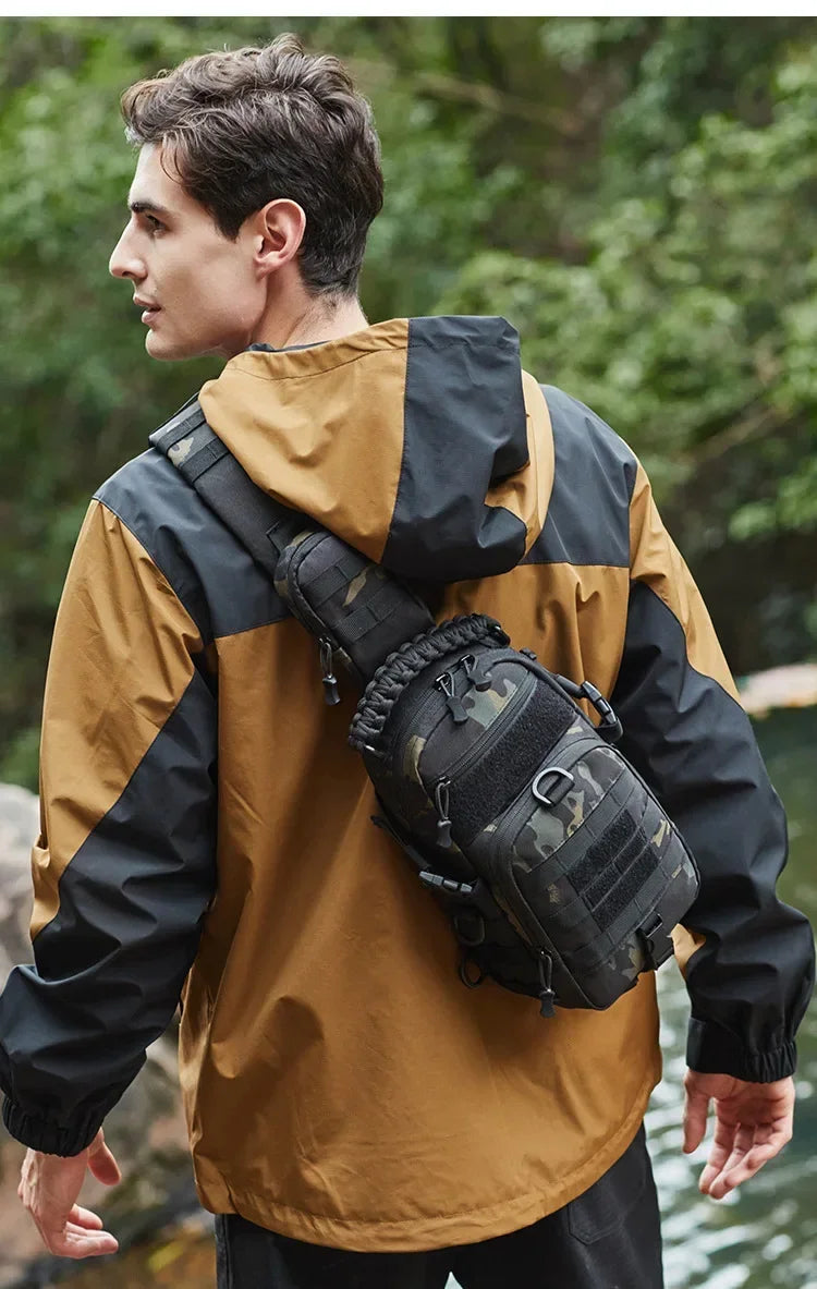 A man wearing a tan and black waterproof jacket carrying a tactical chest bag while outdoors.