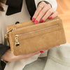 A close-up of a tan retro long wallet with a gold zipper and multiple card slots held by a person.