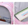 A pink and white Oxford cloth school backpack is shown open, revealing interior compartments and a notebook.