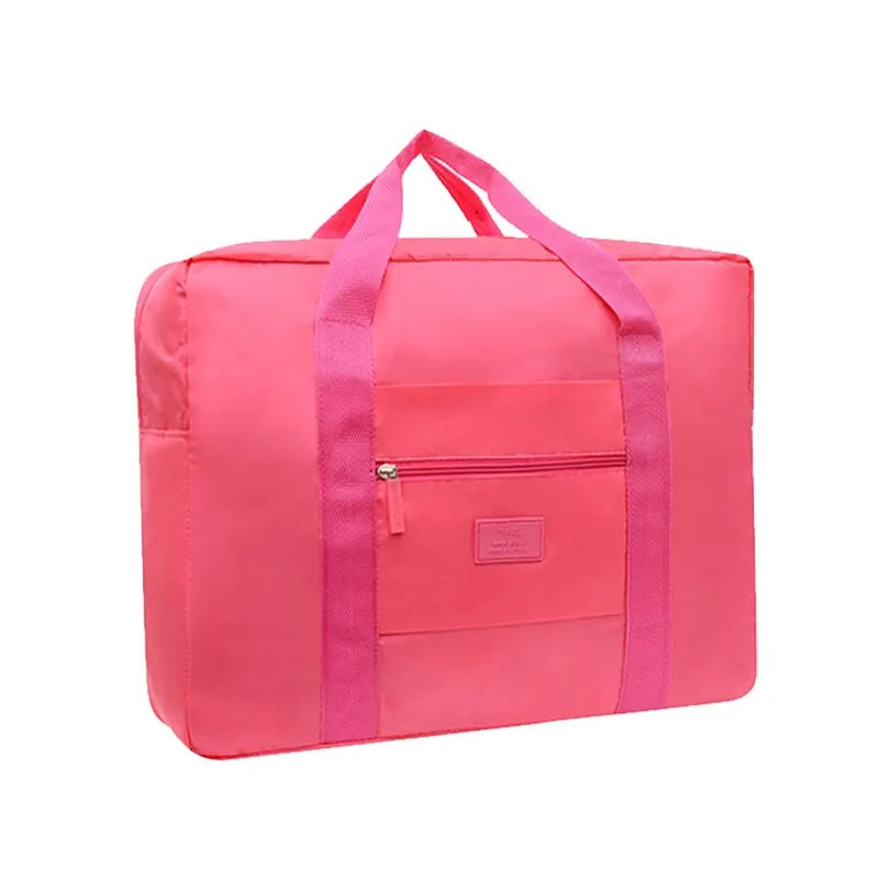A bright pink foldable travel duffel bag with a luggage strap visible on the front pocket.