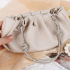 A beige handbag is shown with a crystal rhinestone chain strap featuring knot details.