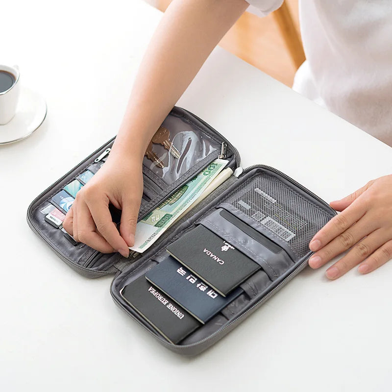 A hand is opening a multi-pocket waterproof travel document organizer containing various currency and cards.