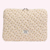 Funda acolchada para portátil con estampado floral color crema y hebilla plateada.