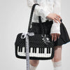 A woman holds a black and white piano print crossbody bag with musical note embroidery.