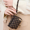 A close-up of a brown patterned accordion card holder wallet with gold accents held by a person wearing a cream blouse.