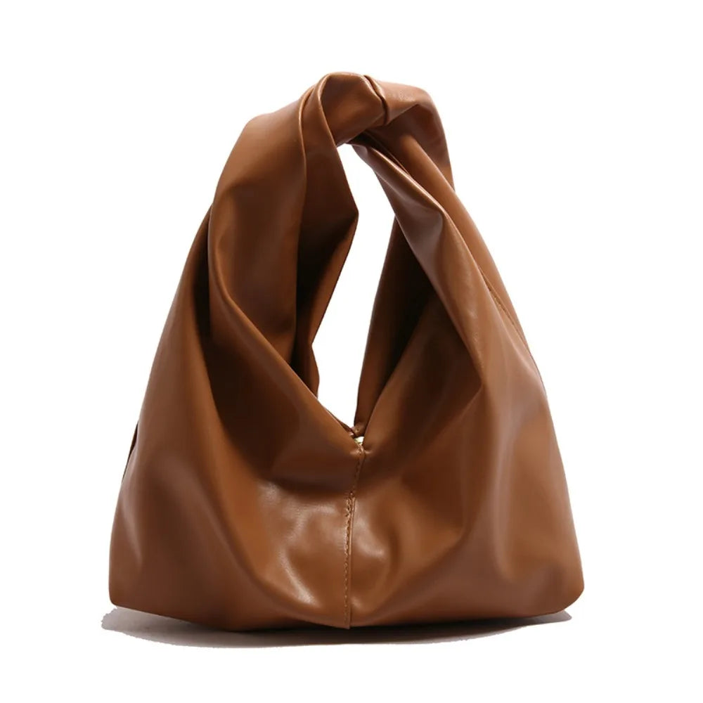 A brown leather minimalist crossbody tote bag folded and displayed against a white background.