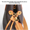 Close-up of a dark brown bag showing an adjustable tan leather shoulder strap detail.