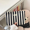 Pochette en crochet rayée tissée noir et blanc, affichée dans une armoire blanche.