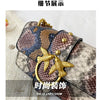 A close-up of an elegant retro crocodile print crossbody bag featuring gold hardware and a bird charm.