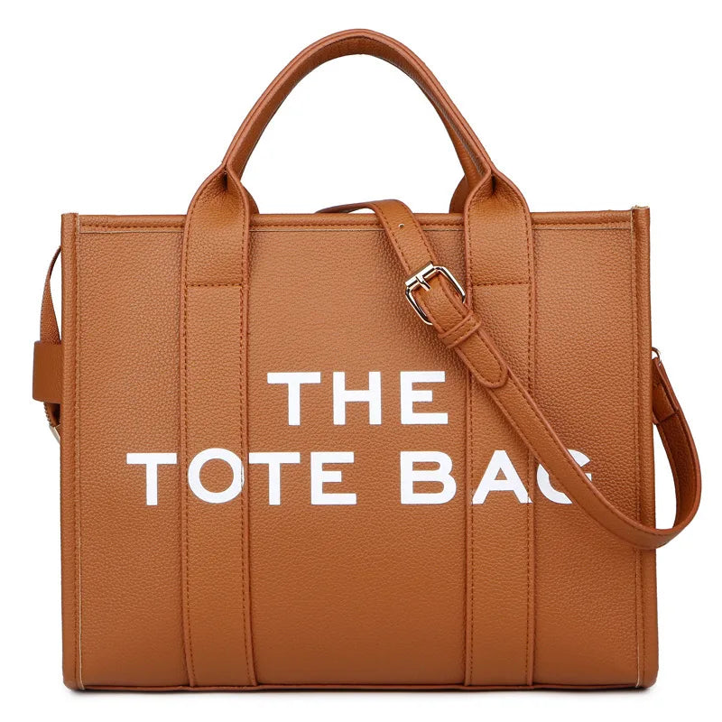Sac cabas en cuir tan avec une sangle marron et du texte blanc indiquant THE TOTE BAG.