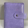 A purple crocodile leather ring binder notebook with a silver snap closure.