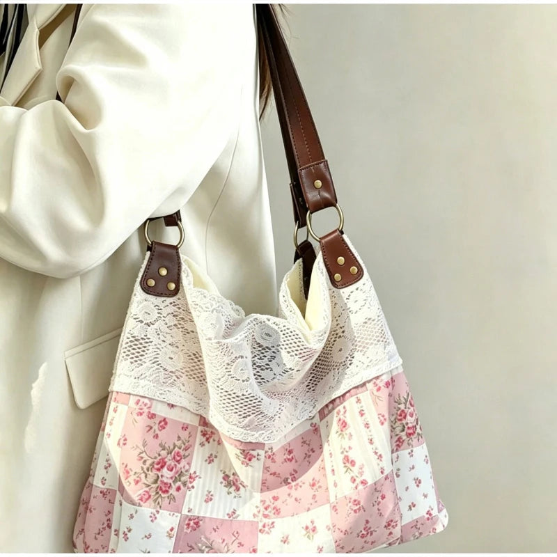 A light pink and white floral patchwork shoulder bag with a sheer lace overlay and brown leather strap.