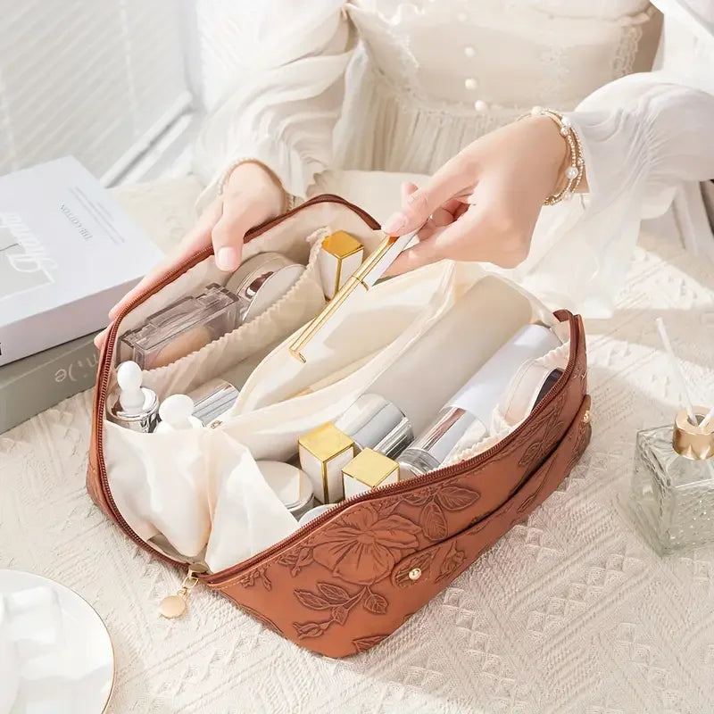 A brown floral makeup tote bag is open, showing various cosmetic products and a gold brush.