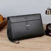 A black men's PU leather clutch bag with a silver hardware logo resting on a wooden surface.