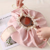 A pink instant-open flat lay makeup organizer bag with a decorative fabric opening is being held by a hand.