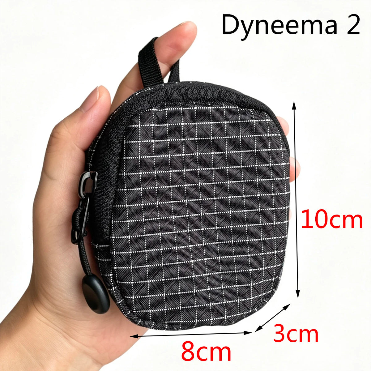 Pochette utilitaire noire en Dyneema 2 pour clés et essentiels, tenue par une main.