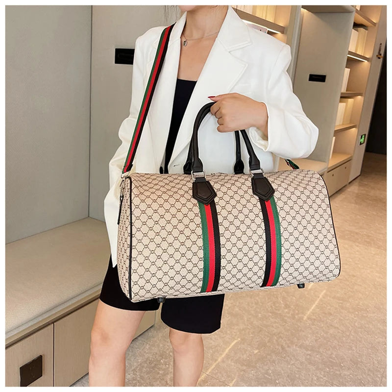 A woman holds a beige plaid travel duffle bag with black and green trim and a white blazer.