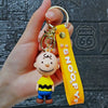 A hand holds a yellow Snoopy silicone keychain featuring the character in a 3D style.