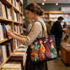 Una mujer sostiene un bolso de tela acolchado vintage con diseños de gallos coloridos en una librería.