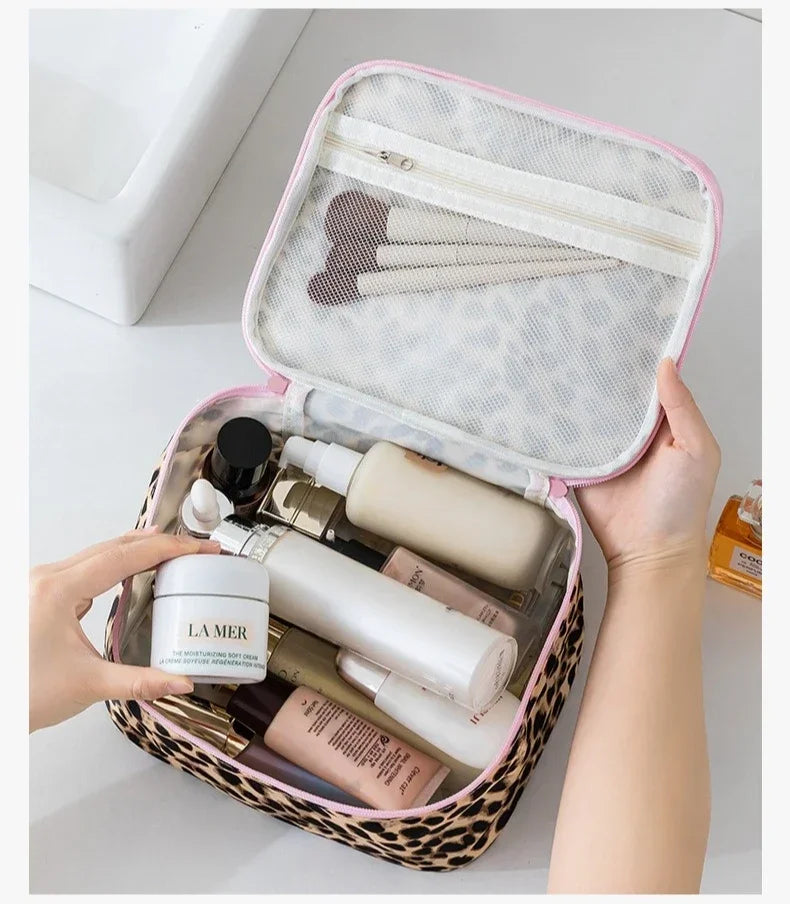 A hand opens a leopard print large capacity waterproof travel makeup organizer bag revealing various cosmetic bottles inside.