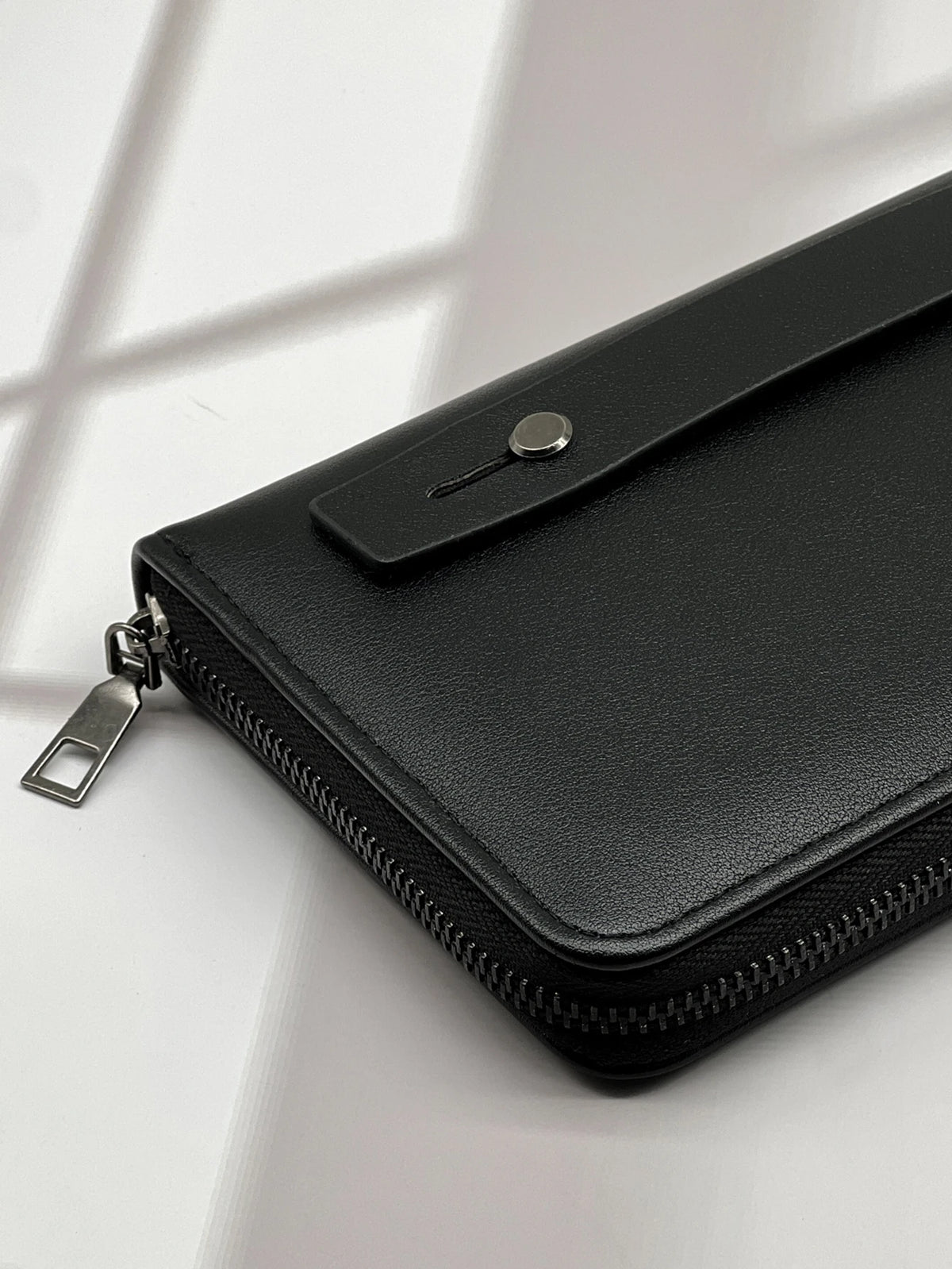 A black multi-card men's commuter wallet with a zippered closure is shown on a white surface.
