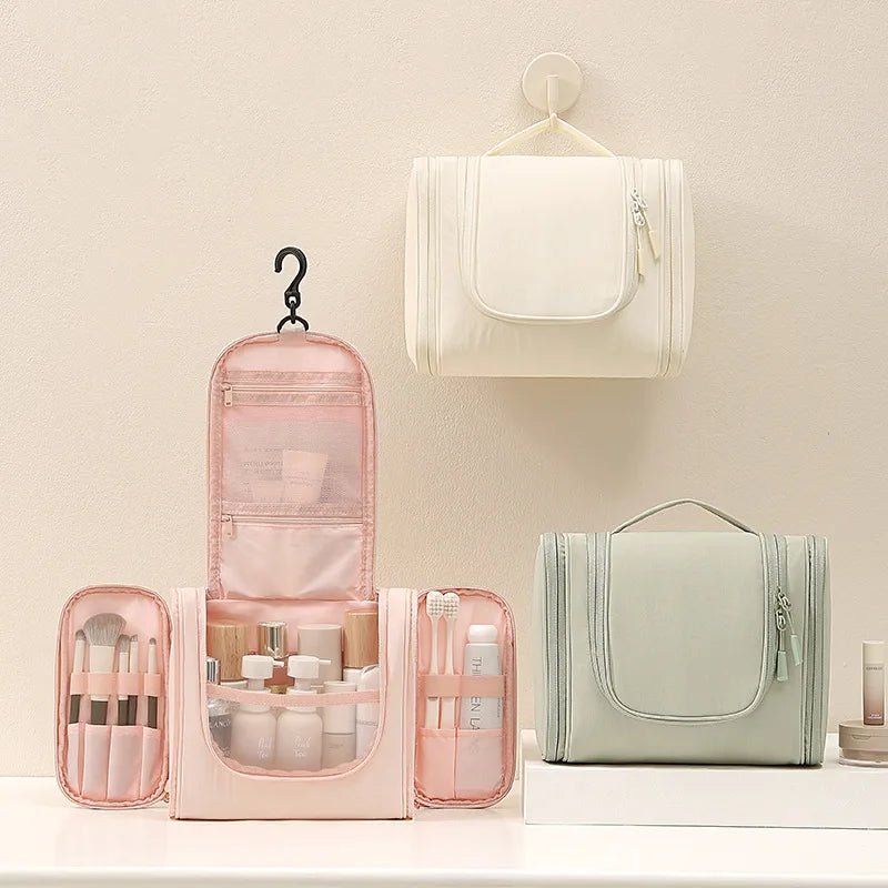 A pink waterproof hanging toiletry bag with a clear window and a light green cosmetic pouch is displayed on a white surface.