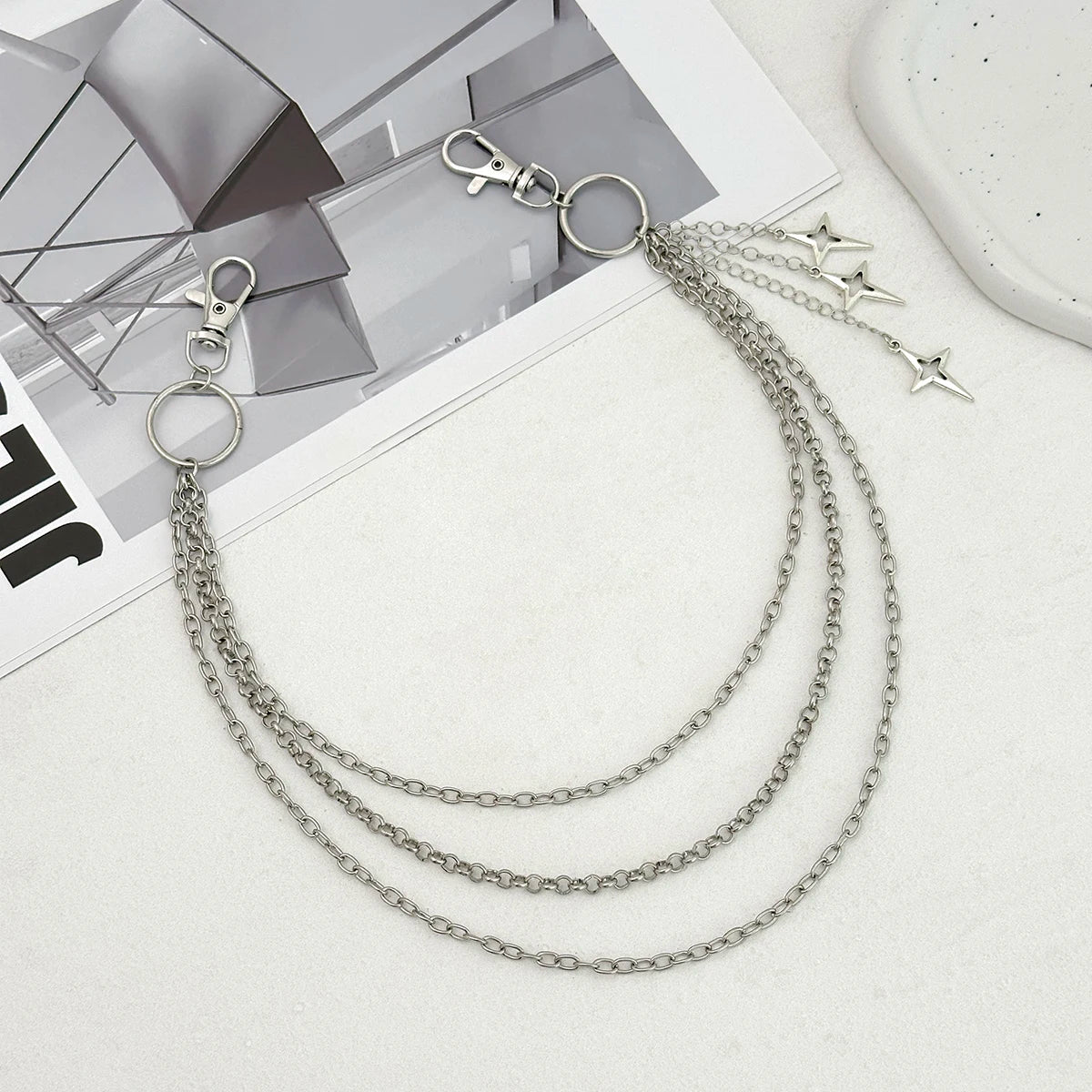 Silver punk star chain belt featuring multiple linked chains and pearl accents displayed on a white surface.