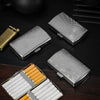 A set of compact metal cigarette cases, including a silver rectangular case and an open box containing 12 orange cigarettes.