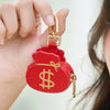 Una mano sostiene una cartera de monedas con forma de corazón y panda de cartón rojo con herrajes dorados.