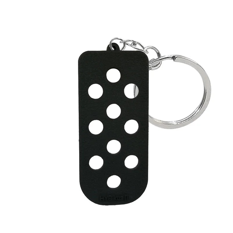 Porte-clés en silicone noir pour chaussure avec trou circulaire et anneau argenté.