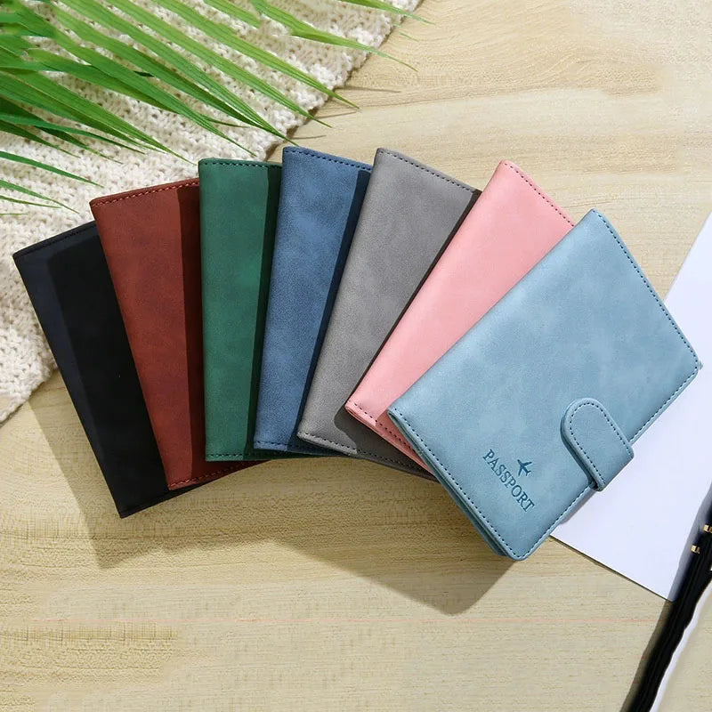 A collection of leather passport and ID holder covers in various shades including brown, green, blue, gray, and pink, laid on