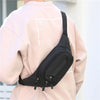 A close-up view of a black canvas waist fanny bag worn on the front of a light pink jacket.