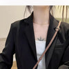 A woman wearing a black blazer is shown with a brown leather modified shoulder strap accessory.