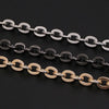 Three strands of adjustable metal chain straps in silver, black, and gold lay across a dark background.