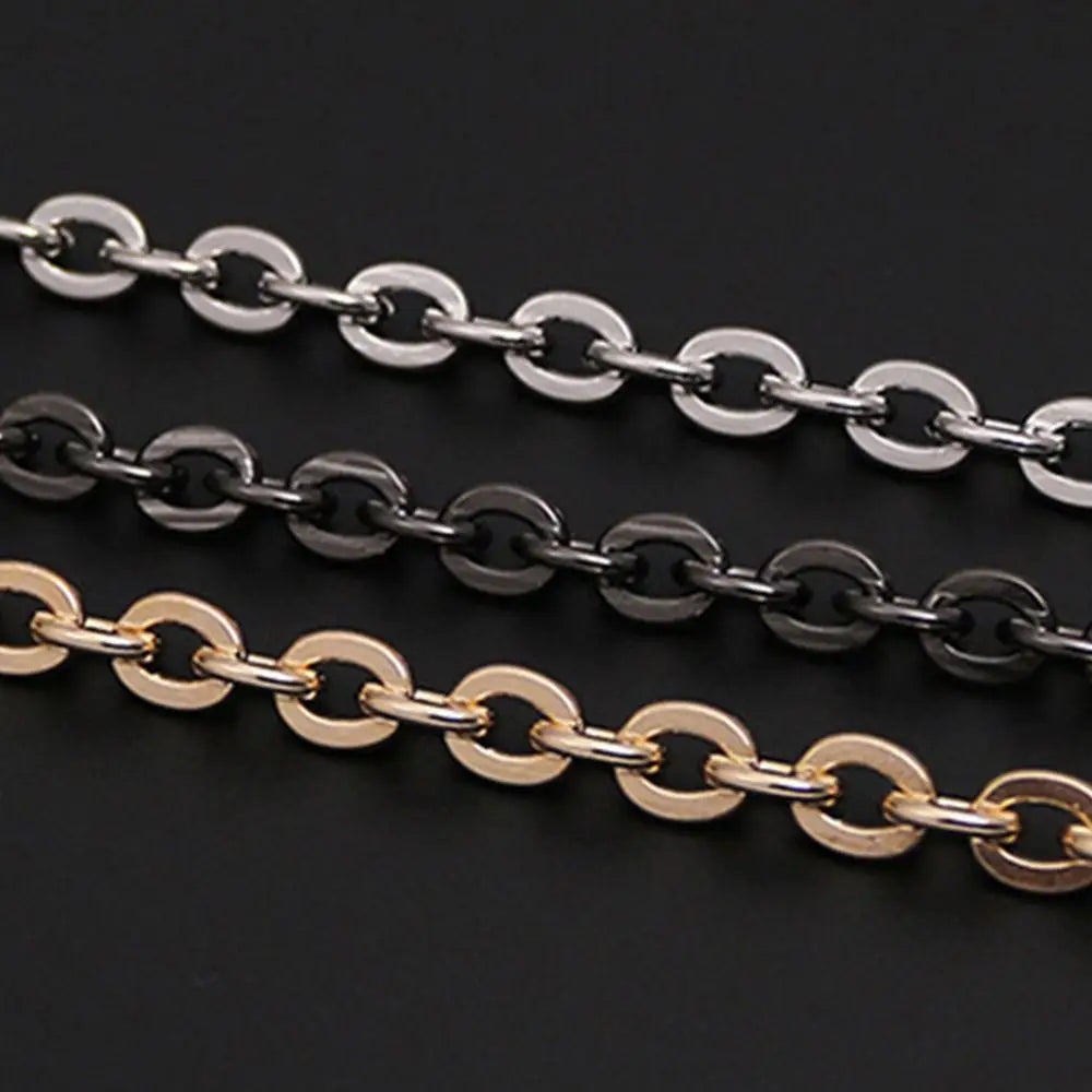 Three strands of adjustable metal chain straps in silver, black, and gold lay across a dark background.