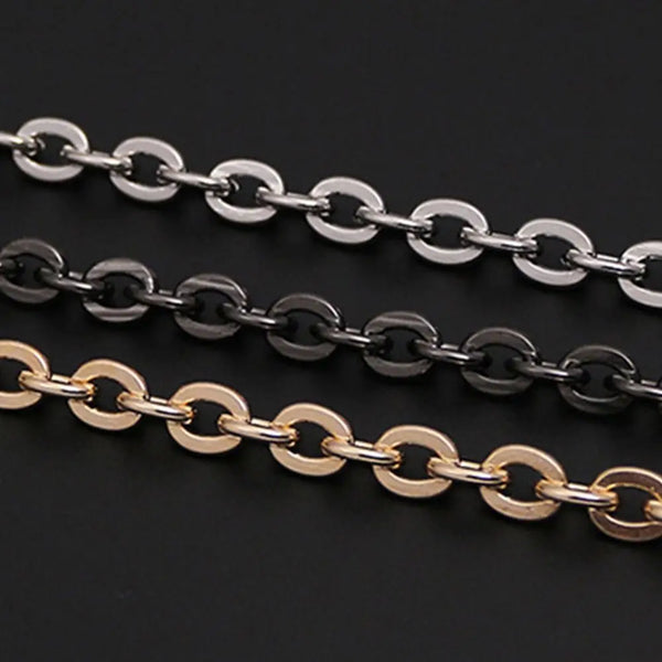 Three strands of adjustable metal chain straps in silver, black, and gold lay across a dark background.