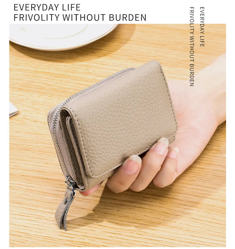 Cartera pequeña de cuero genuino de vaca color beige claro con cremallera, sostenida en la mano sobre una superficie de mader
