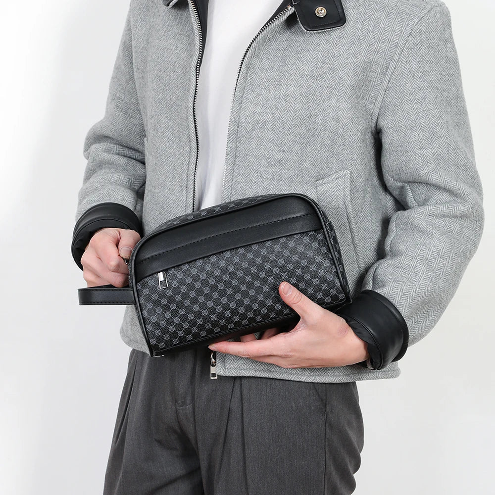 A person holds an elegant black PU leather clutch bag against a gray jacket and dark pants.